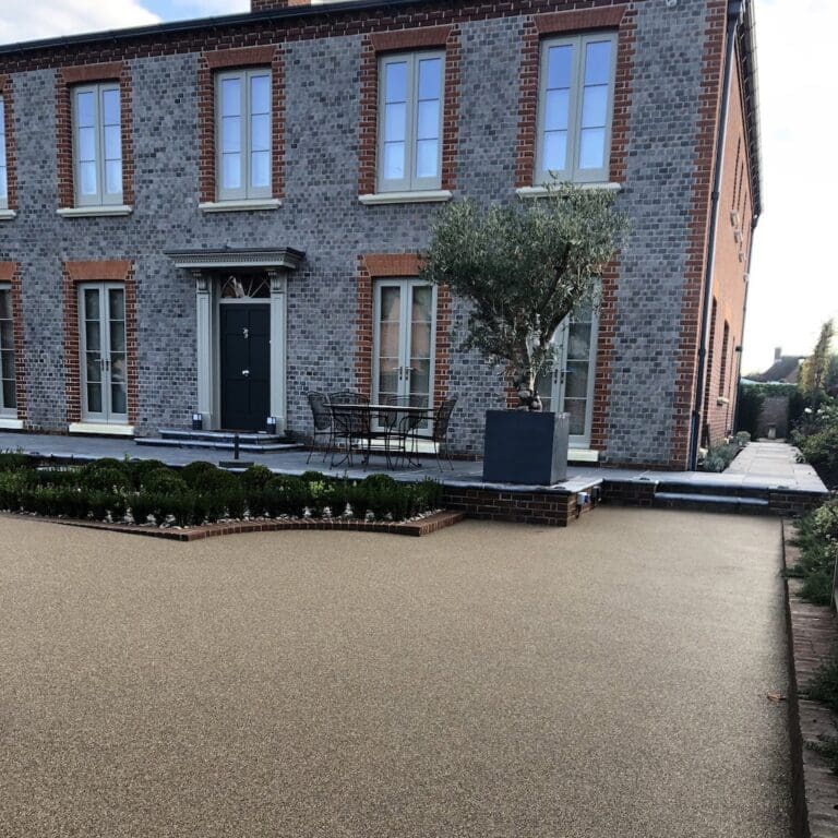 Brown resin driveway installation for a large bricked house