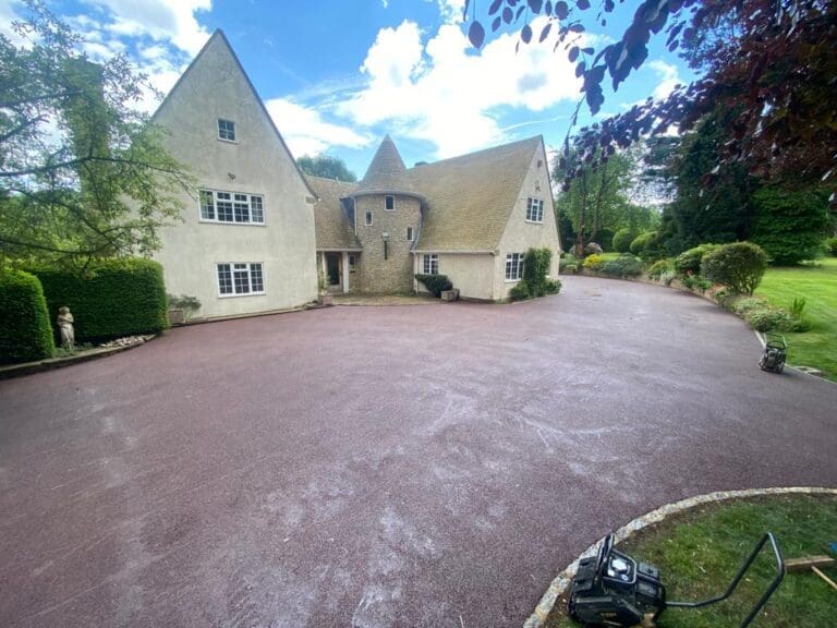 Red coloured resin driveway installation for large house with turrets