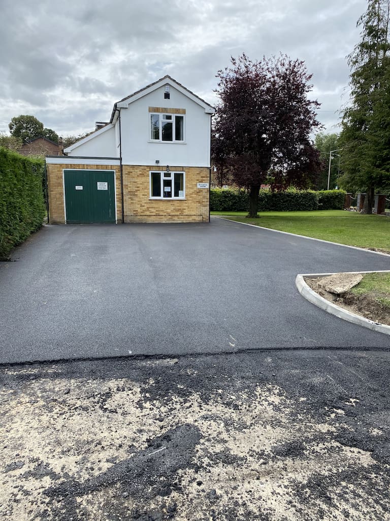 Detached house with new tarmac driveway installation leading to door and garage