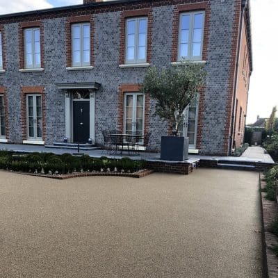 Brown resin driveway installation for a large bricked house