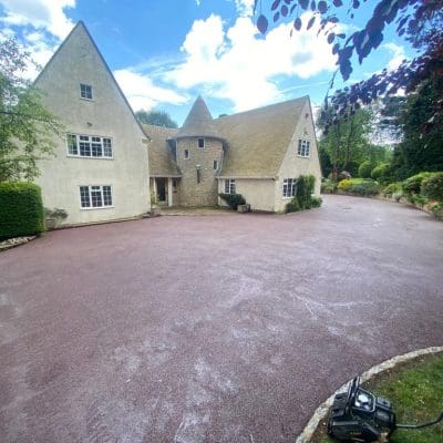 Red coloured resin driveway installation for large house with turrets